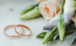 two wedding bands next to a bouquet of flowers