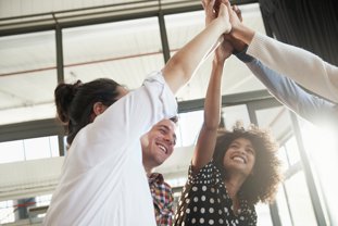 Group of business colleagues high-fiving each other in the office