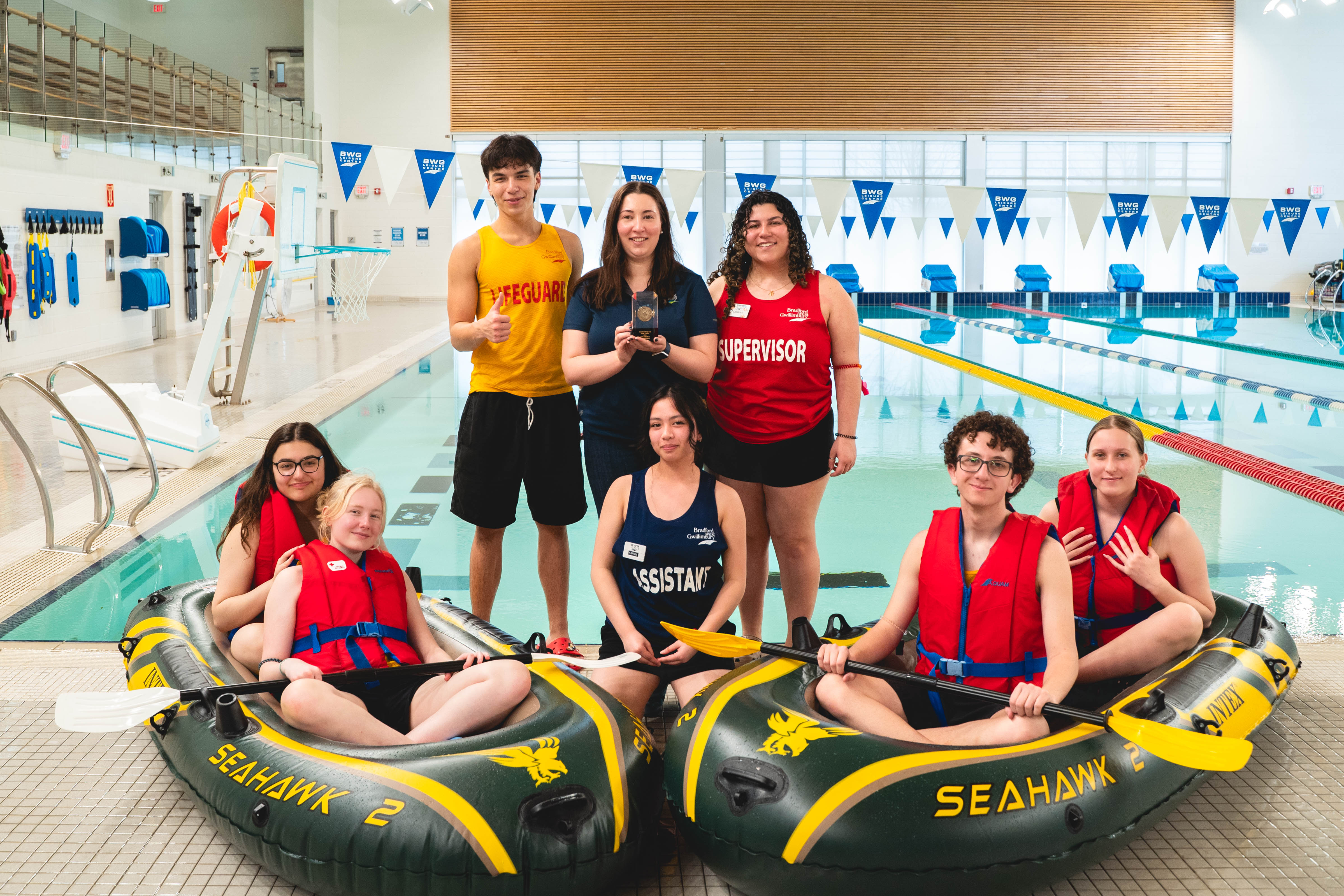 Image of individuals by the pool with floatation devices and lifeguards