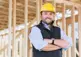 Residential builder on a project site, framed home in the background
