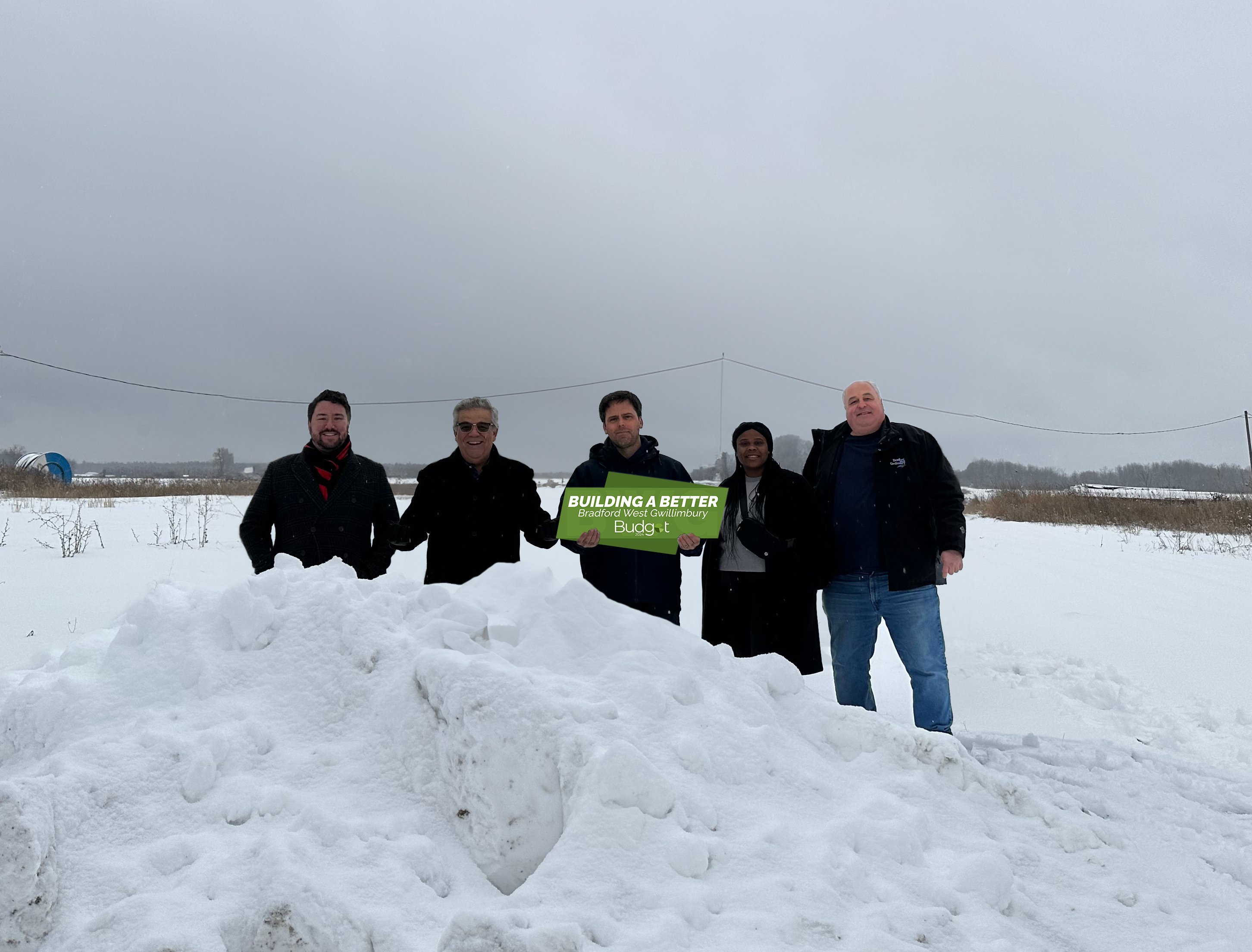 BWG Council members at the future site of the Snow Disposal Facility at 225 Dissette Street, holding a sign that reads "Building a Better Bradford West Gwillimbury" and includes the Budget 2024 logo;  