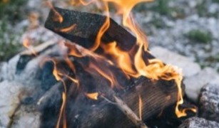 Up close image of an outdoor firepit with two marshmallows roasting over it