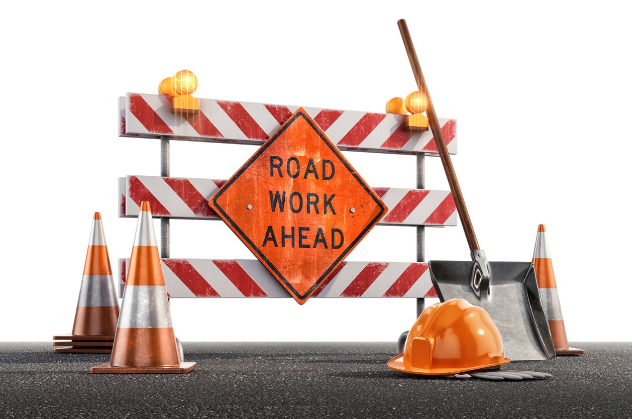 image of road work ahead sign with construction barrier, pilons and shovels