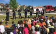 Group of students sitting on a lawn, learning about fire safety from fire prevention staff